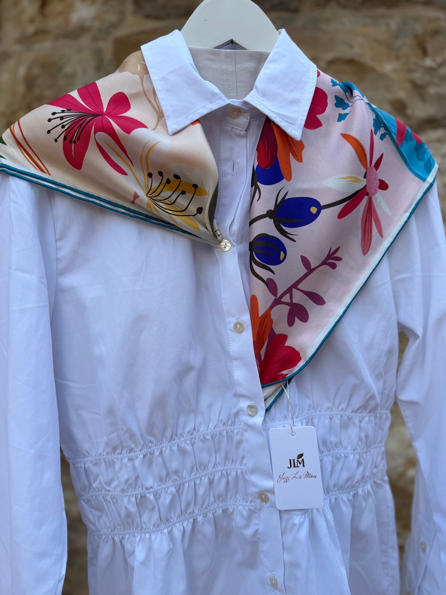 White shirt with colorful floral scarf draped over the collar. Neck scarf by Jazz La Moie